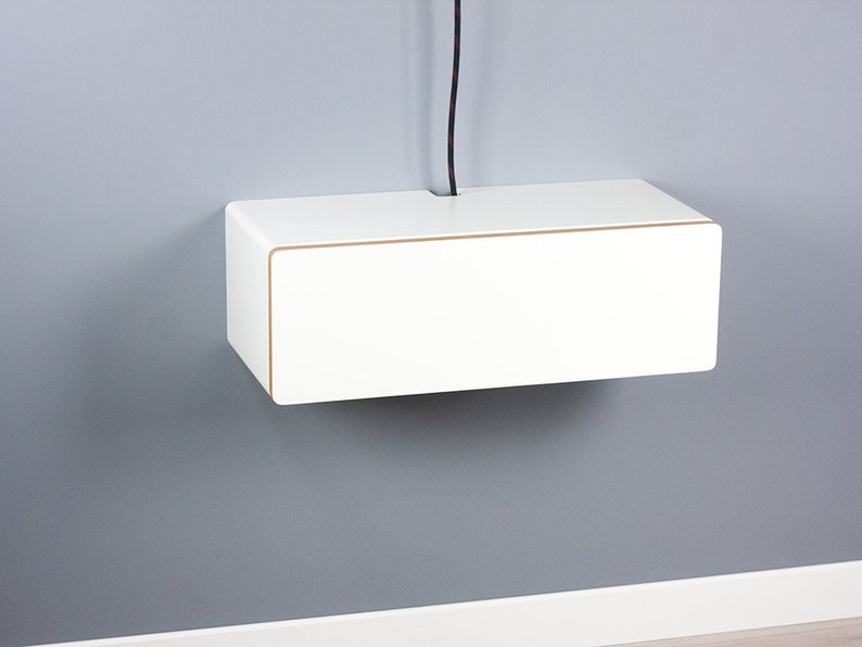 May include: White floating shelf with a cable management slot. The shelf is mounted on a gray wall.