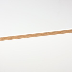 May include: White floating shelf with a wood trim around the edge.