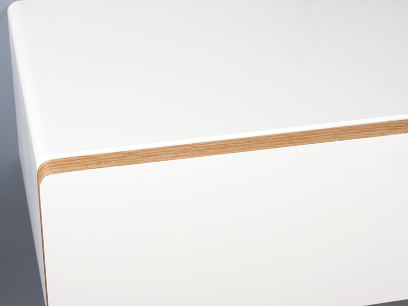 May include: White floating shelf with a wood trim around the edge.