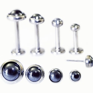 May include: A set of 9 black gemstone body jewelry, including a variety of sizes and styles. The jewelry is made of surgical steel and features black gemstones.