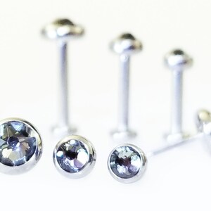 May include: Five silver nose studs with clear gemstones. The studs are different sizes and have a flat back.