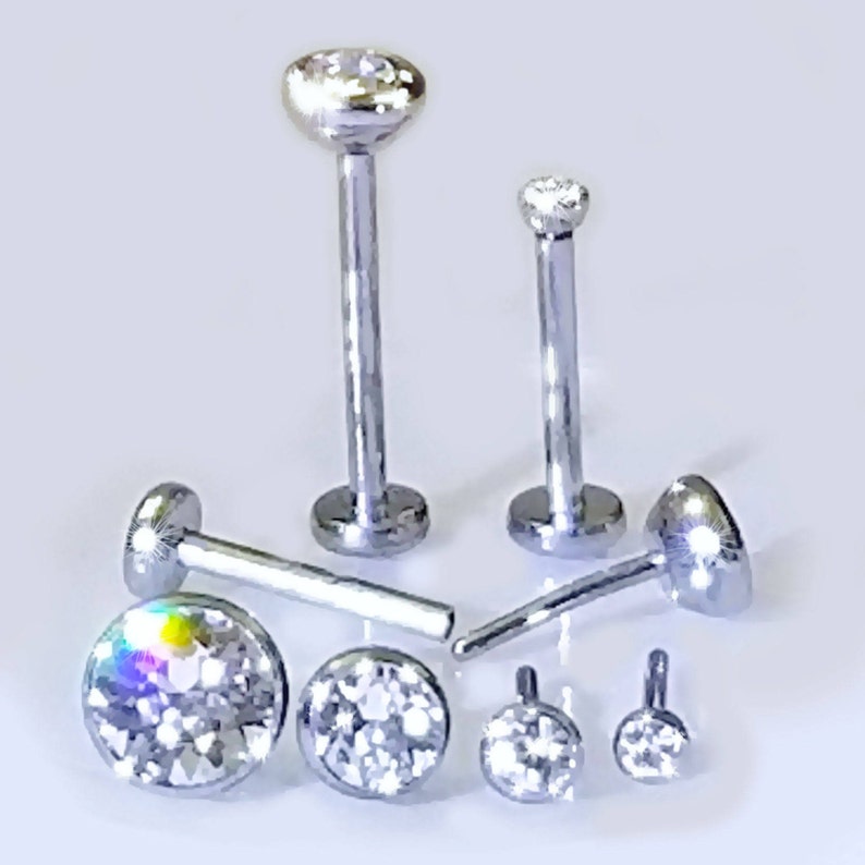 May include: A set of seven silver body jewelry pieces with clear crystal accents. The jewelry is made of surgical steel and is available in different sizes.