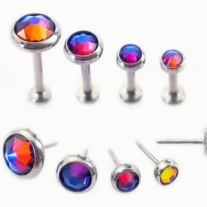 May include: A set of eight surgical steel body jewelry pieces with iridescent rainbow colored gem tops. The gems are round and come in various sizes. The jewelry is suitable for cartilage, helix, conch, tragus, and lobe piercings.