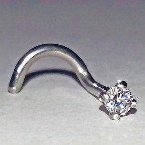 May include: A silver nose ring with a clear round gemstone.