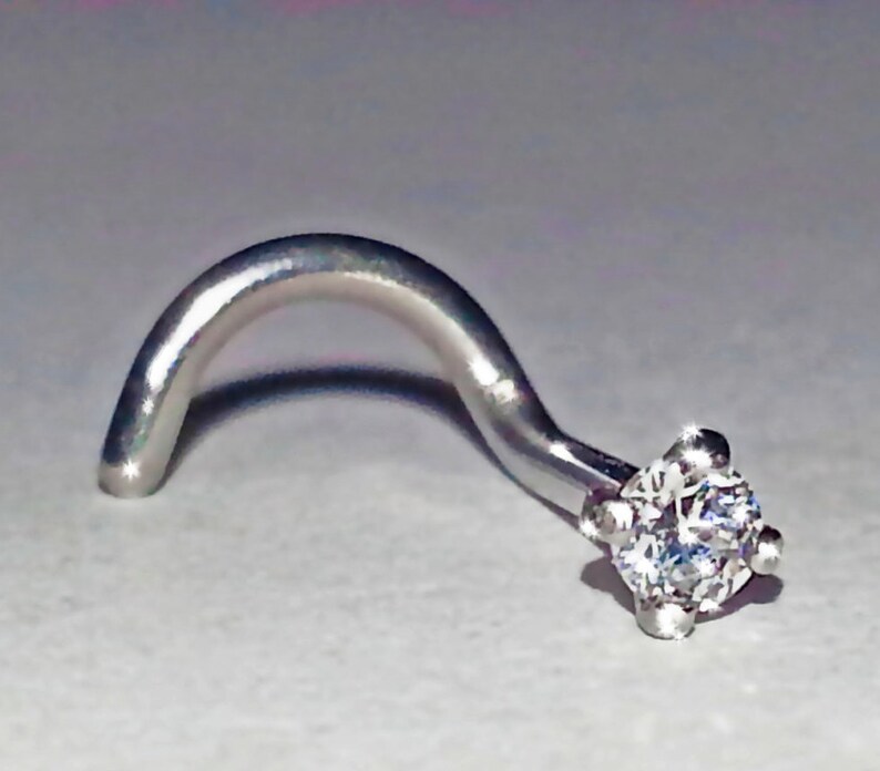 May include: A silver nose ring with a clear round gemstone.