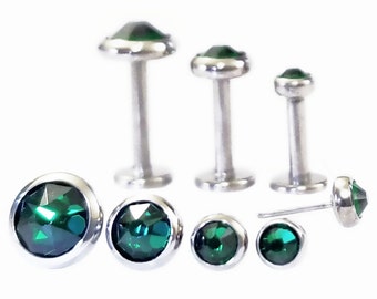 Könnte beinhalten: Ein Set aus sieben Körperschmuckstücken aus chirurgischem Stahl mit smaragdgrünen Edelsteinen. Das Set enthält drei verschiedene Größen von Labret-Steckern und vier verschiedene Größen von Edelsteinen.