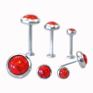 May include: A set of six red opal body jewelry. The jewelry is made of surgical steel and features a round red opal stone.