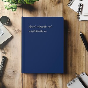 May include: A navy blue journal with the text "Aligned, unstoppable, and unapologetically me." printed in silver on the front cover.