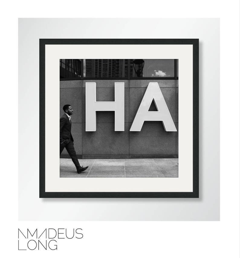 Op de afbeelding: Zwart-witfoto van een man die langs een gebouw loopt met het woord "HA" in grote witte letters aan de zijkant.