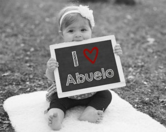 Puede incluir: Un niño pequeño sosteniendo una pizarra negra con las palabras "I love Abuelo" escritas con tiza blanca. Un corazón rojo está dibujado al lado de la palabra "love".