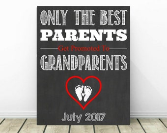 Könnte beinhalten: Schwarzes Schild aus Schiefer mit weißem Text, der "Only the best parents get promoted to grandparents" lautet, mit einem roten Herzen, das weiße Baby-Fußabdrücke enthält, und dem Datum "July 2017".