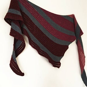 May include: A burgundy and grey striped crocheted shawl with a scalloped edge.