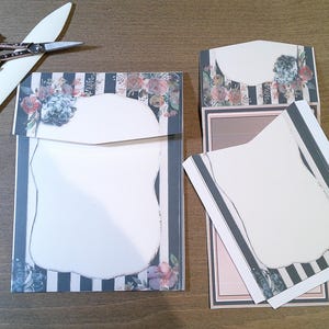May include: Two blank cards with floral designs and black and white stripes. The cards are folded in half and have a scalloped edge.