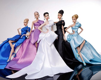 May include: Five fashion dolls wearing elegant gowns in various colors, including blue, purple, white, black, and light blue. The dolls are posed in a group, showcasing their elaborate dresses and accessories.