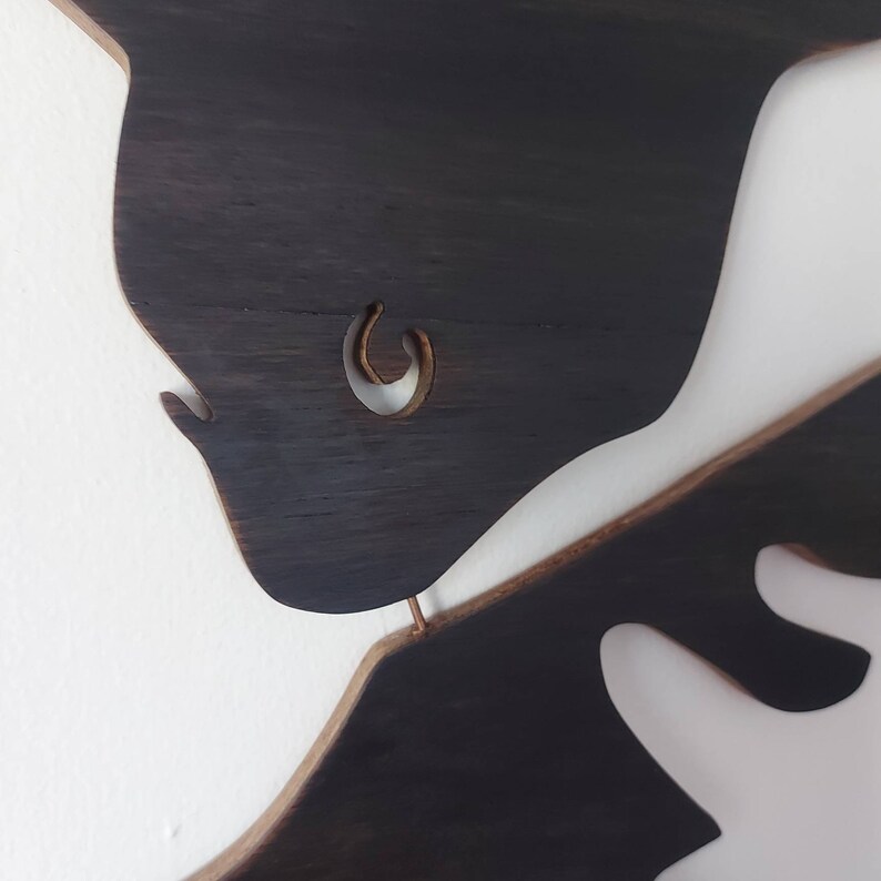 Puede incluir: Dos piezas de arte de pared de madera marr&oacute;n oscuro en forma de figuras abstractas. La pieza superior tiene un recorte en forma de c&iacute;rculo.