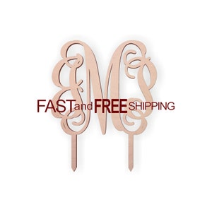 May include: Wooden cake topper with a decorative, cursive letter "M" in a light brown color. The topper is on two wooden sticks.