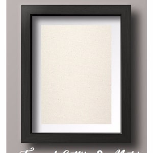 May include: A black picture frame with a white mat and a white canvas insert. The frame is on a gray background. "Framed Cotton & Mat" is written in white cursive below the frame.