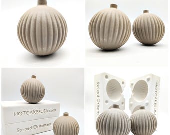 May include: Two gray, ribbed, round ornaments made from a silicone mold. The mold is labeled "Striped Ornament" and "HOTCAKESUSA.com".