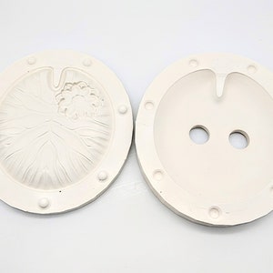 May include: Two white silicone molds for making resin crafts. One mold features a detailed lotus flower design, while the other has two round holes.