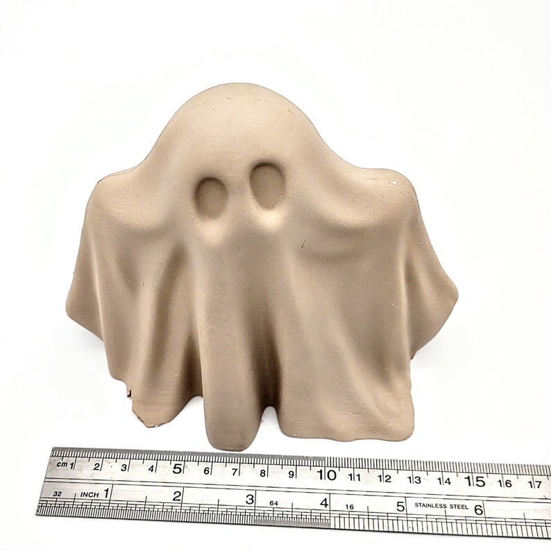 May include: A beige ceramic ghost figurine with two eyes. The ghost is about 5 inches tall.