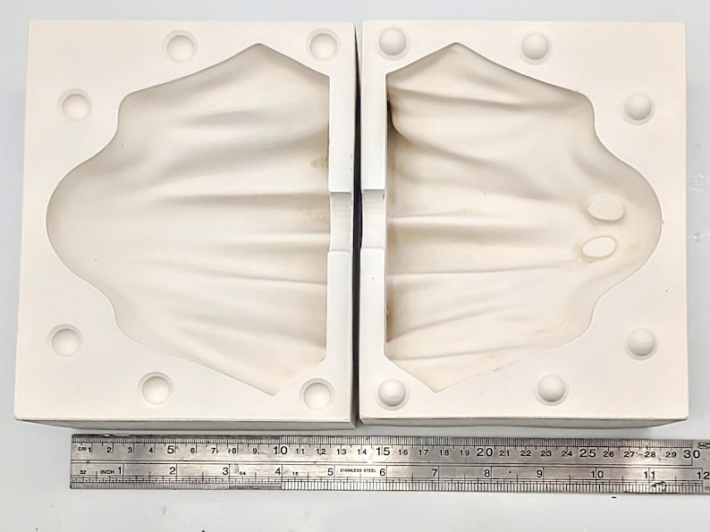 May include: Two-piece white silicone mold for making a ghost-shaped cake or other dessert. The mold is approximately 12 inches wide and 15 inches long.