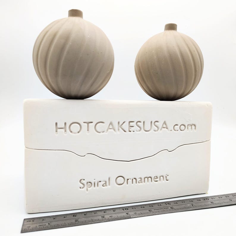 May include: Two brown ceramic spiral ornament molds on a white mold base. The base has the text "HOTCAKESUSA.com" and "Spiral Ornament" on it. A ruler is in the bottom of the image.