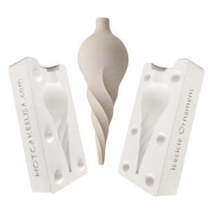 May include: A beige, spiral-shaped icicle ornament positioned between two white plaster mold halves. The left mold is embossed with the text HOTCAKESUSA.COM and the right mold is embossed with the text ICICICLE ORNAMENTS.