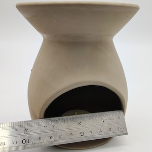 May include: A terracotta-colored ceramic oil burner with a round opening for a tea light candle. The burner is approximately 3 inches in diameter.