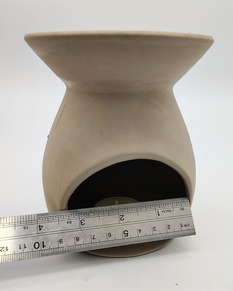 May include: A terracotta-colored ceramic oil burner with a round opening for a tea light candle. The burner is approximately 3 inches in diameter.