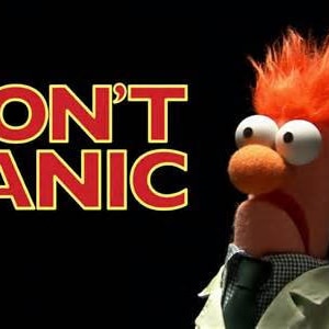 Pode incluir: Um gr&aacute;fico vermelho e amarelo com o texto "DON'T PANIC" e um fantoche de cabelo ruivo com uma express&atilde;o preocupada vestindo um jaleco branco e uma gravata azul escura.