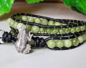Puede incluir: Un brazalete de cuero negro con cuentas de piedras preciosas verdes y un dije de rana de plata.