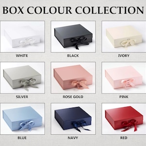 May include: A collection of nine square gift boxes with ribbon closures, labeled BOX COLOUR COLLECTION. Colors include white, black, ivory, silver, rose gold, pink, blue, navy, and red. Each box features a matching ribbon tied in a bow at the front.