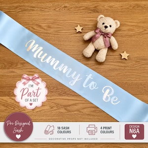 May include: A light blue satin sash featuring the white script text Mummy to Be, accompanied by a small knitted beige teddy bear with a mauve ribbon, two wooden star cutouts, and a circular badge with the text I'M Part OF A SET.