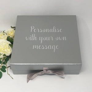 May include: A silver gift box with a satin ribbon. The box has the text "Personalise with your own message" engraved on the top.