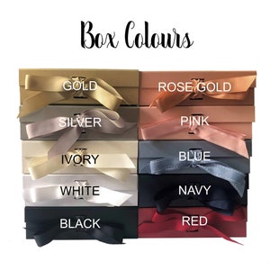 May include: A display of eight different colored gift boxes with matching ribbon. The colors are gold, rose gold, pink, blue, ivory, white, navy, and red. The boxes are arranged in two rows of four. The text "Box Colours" is at the top of the image.