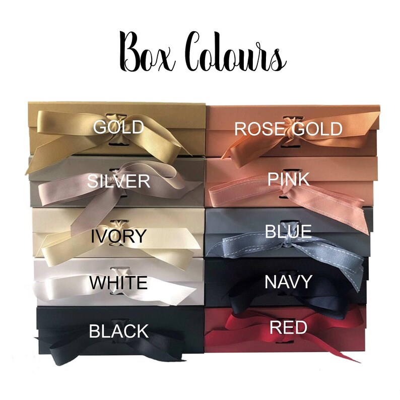 May include: A display of eight different colored gift boxes with matching ribbon. The colors are gold, rose gold, pink, blue, ivory, white, navy, and red. The boxes are arranged in two rows of four. The text "Box Colours" is at the top of the image.