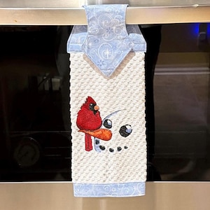 Snowman with a Cardinal Embroidered  on his carrot nose.  Hanging white waffle weave kitchen towel.