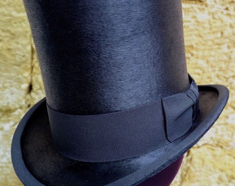 May include: A black top hat with a black ribbon band. The hat is made of a smooth, shiny material.