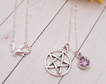 Puede incluir: Un collar de cadena de plata con un colgante de pentáculo de plata y un pequeño amuleto de cristal morado.