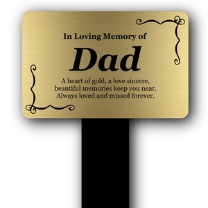 May include: A gold-coloured memorial stake with the words "In Loving Memory of Dad" in black text. The stake includes a heartfelt message and decorative flourishes.