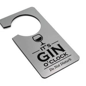 May include: A silver door hanger with a black silhouette of a martini glass and the text "It's Gin o'Clock Do Not Disturb".