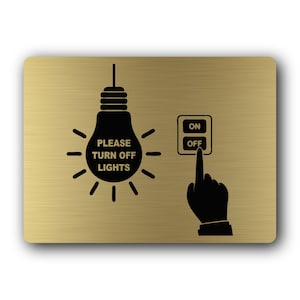 May include: A rectangular gold-colored sign with a brushed metal finish. It features a black graphic of a lightbulb with the text PLEASE TURN OFF LIGHTS inside, alongside a black graphic of a hand pressing the OFF button on a light switch.