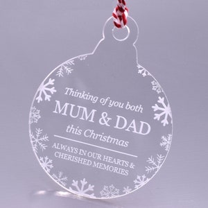 May include: Clear acrylic Christmas bauble with a white snowflake design and the text "Thinking of you both MUM & DAD this Christmas ALWAYS IN OUR HEARTS & CHERISHED MEMORIES".