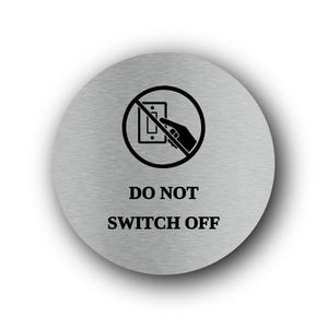 May include: A circular brushed silver metal sign featuring a black graphic of a hand reaching toward a light switch inside a prohibition circle with a diagonal line. Below the graphic, the text reads DO NOT SWITCH OFF in black font.