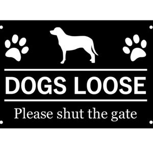 Op de afbeelding: Zwart rechthoekig bord met witte tekst en afbeeldingen. Het bord toont een honden silhouet, pootafdrukken en de woorden "DOGS LOOSE" boven "Please shut the gate."