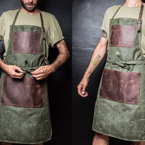 May include: A green canvas apron with brown leather accents and two large pockets. The apron has adjustable straps and a tie at the waist.