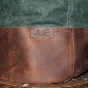 May include: A brown leather tote bag with a green canvas top. The bag has a leather strap and a personalized label that reads "JJF".