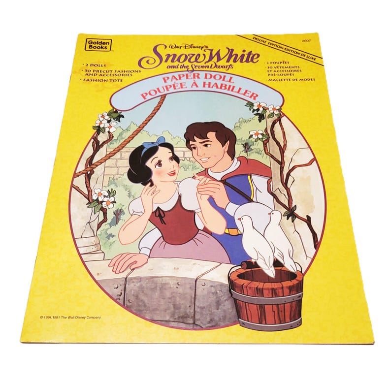 May include: A vintage Golden Books Snow White and the Seven Dwarfs paper doll set. The cover features an illustration of Snow White and the Prince, with doves and a wooden bucket. The text includes "Paper Doll" and "Deluxe Edition".