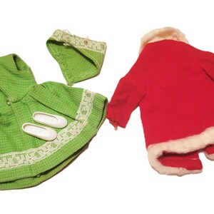 May include: A collection of doll clothes, including a green dress with a matching bonnet and white shoes, and a red coat with white trim. The dress has a textured pattern and lace trim.