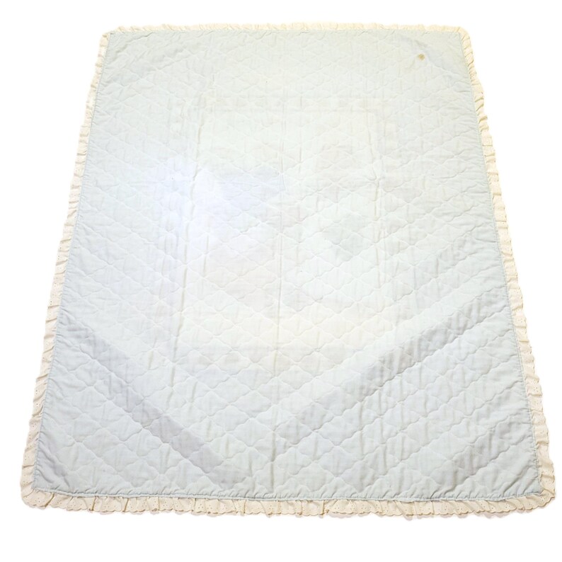 May include: A light blue quilted blanket with a white lace trim. The blanket is made of a soft, comfortable fabric and is perfect for snuggling up on the couch.